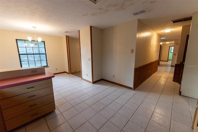 unfurnished room with light tile patterned floors, a textured ceiling, and a notable chandelier