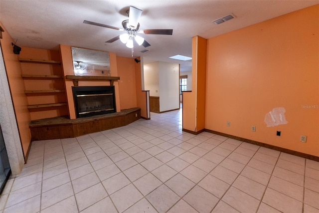 unfurnished living room featuring a skylight, ceiling fan, light tile patterned floors, and a textured ceiling