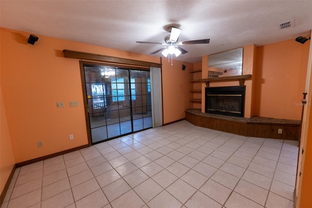 unfurnished living room with ceiling fan, light tile patterned flooring, and a textured ceiling