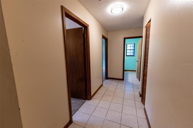 hallway with light tile patterned flooring and a textured ceiling