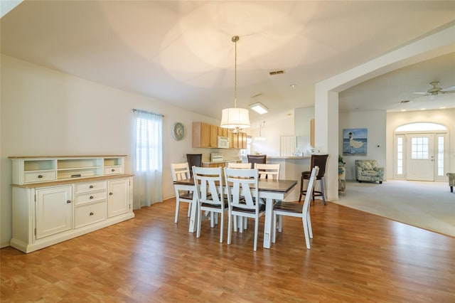 carpeted dining area featuring ceiling fan and vaulted ceiling