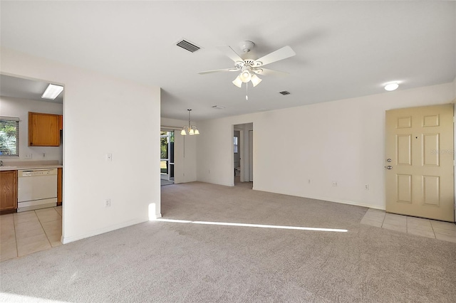 unfurnished living room with ceiling fan with notable chandelier, a healthy amount of sunlight, and light colored carpet