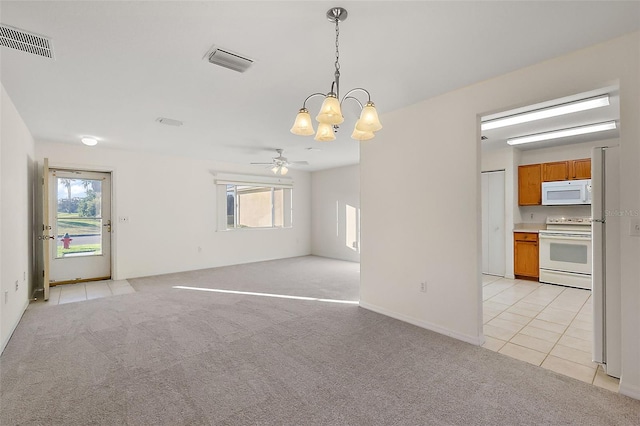 spare room featuring ceiling fan with notable chandelier, light colored carpet, and plenty of natural light