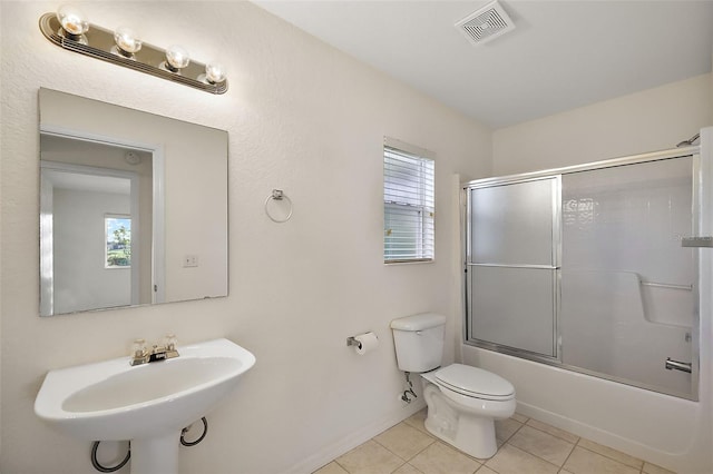 full bathroom with shower / bath combination with glass door, sink, tile patterned flooring, and toilet