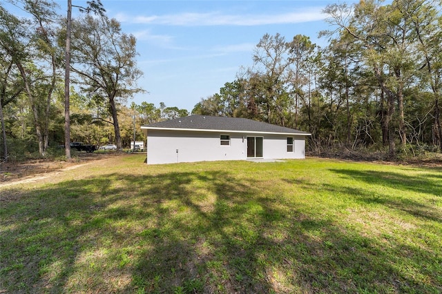 back of house featuring a lawn and stucco siding