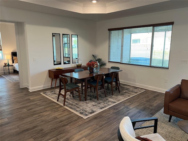 dining room featuring dark hardwood / wood-style flooring, ornamental molding, and a raised ceiling