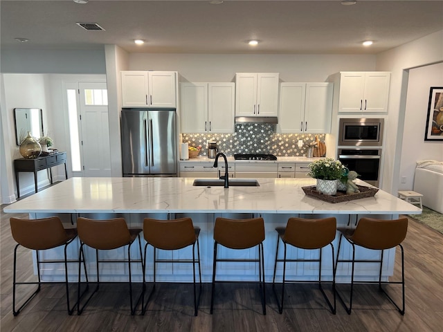 kitchen featuring white cabinetry, sink, appliances with stainless steel finishes, and a large island with sink