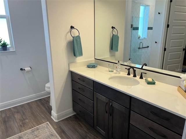 bathroom featuring wood-type flooring, vanity, toilet, and a shower with shower door