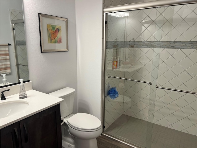 bathroom featuring hardwood / wood-style flooring, a shower with shower door, vanity, and toilet