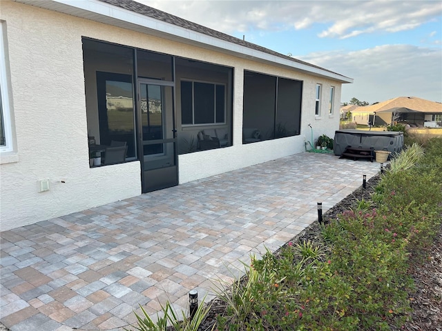 view of patio / terrace featuring a hot tub and a sunroom