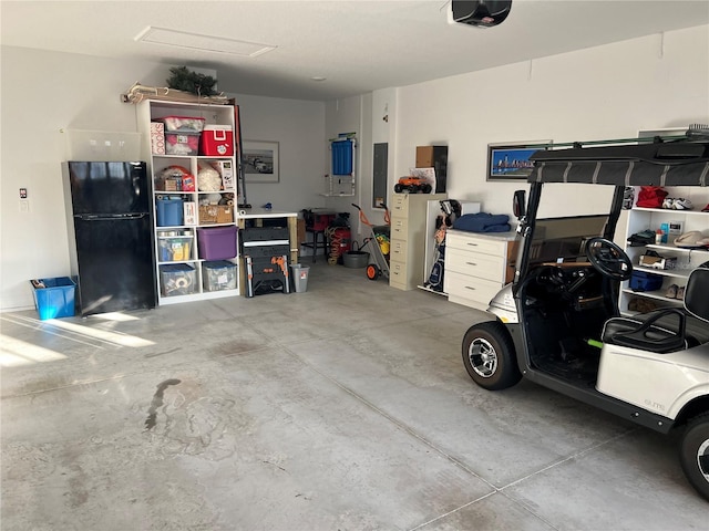 garage featuring electric panel, black fridge, and a garage door opener