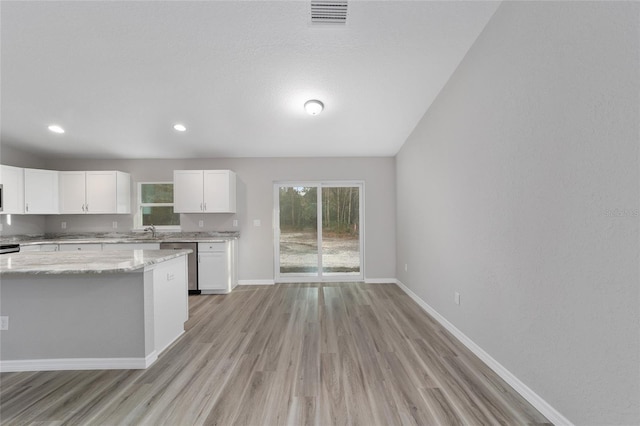 kitchen featuring white cabinetry, light hardwood / wood-style floors, dishwasher, light stone counters, and sink