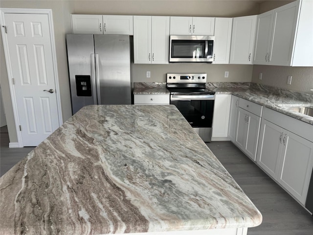 kitchen featuring appliances with stainless steel finishes, white cabinetry, and light stone countertops