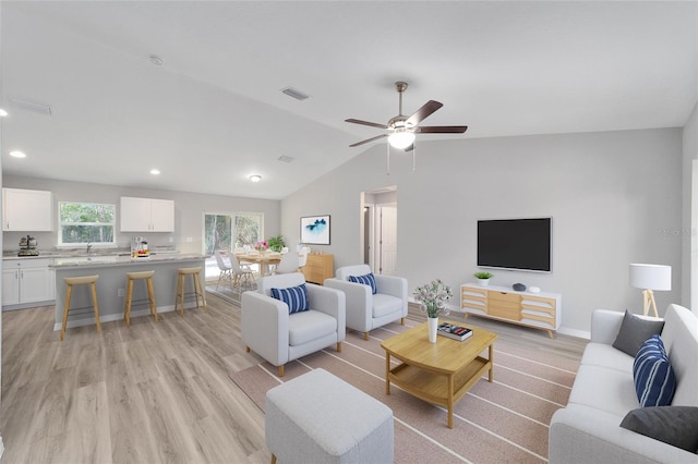 living room featuring ceiling fan, vaulted ceiling, sink, and light hardwood / wood-style floors