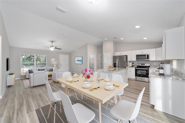 dining space featuring ceiling fan, light wood-type flooring, and vaulted ceiling