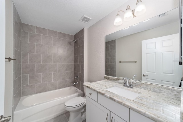 full bathroom with a textured ceiling, tiled shower / bath, tile patterned floors, vanity, and toilet