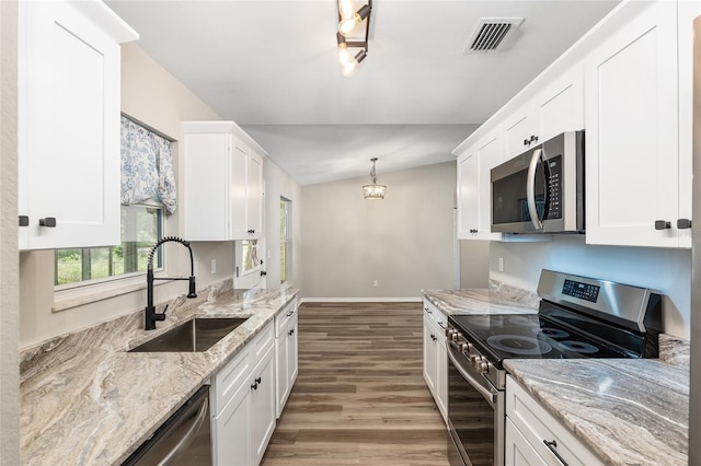 kitchen featuring white cabinets, appliances with stainless steel finishes, and lofted ceiling