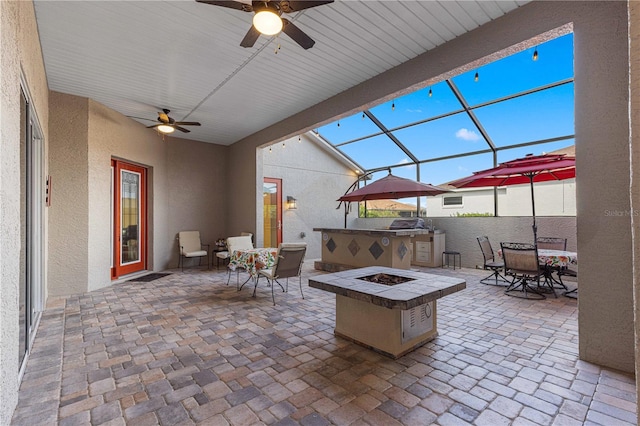 view of patio with ceiling fan, a lanai, and a fire pit