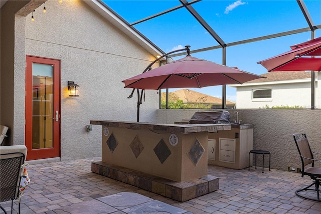 view of patio with area for grilling and glass enclosure