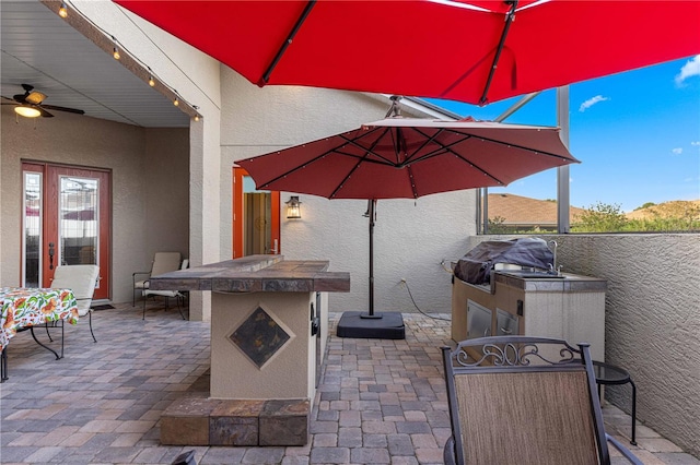 view of patio featuring ceiling fan, a grill, and exterior kitchen