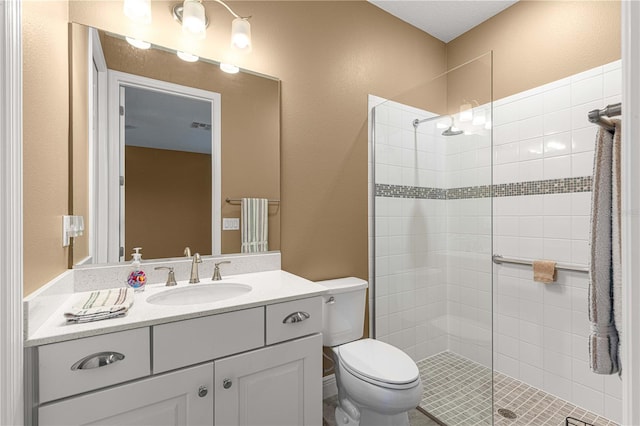 bathroom featuring vanity, toilet, and a tile shower