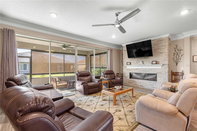 living room with light wood-type flooring, a large fireplace, a textured ceiling, and crown molding