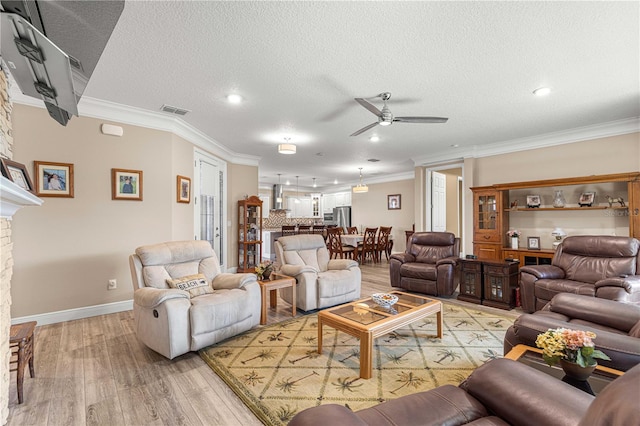 living room featuring light hardwood / wood-style floors, ceiling fan, a textured ceiling, and ornamental molding