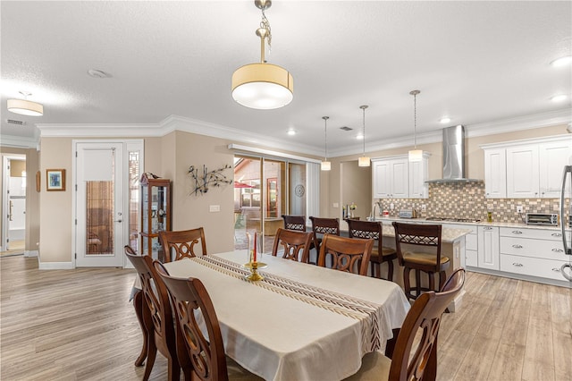 dining area featuring light hardwood / wood-style floors, a textured ceiling, and ornamental molding