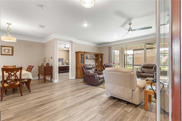 living room with a textured ceiling, crown molding, and light hardwood / wood-style flooring