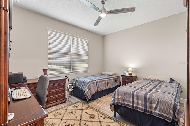 bedroom with a textured ceiling, light hardwood / wood-style flooring, and ceiling fan