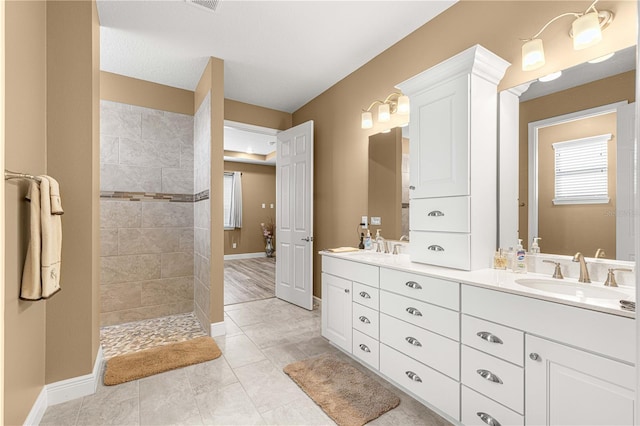 bathroom with vanity, a textured ceiling, tile patterned floors, and a tile shower