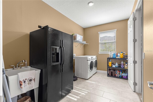 laundry room with sink, washing machine and clothes dryer, light tile patterned floors, and a textured ceiling