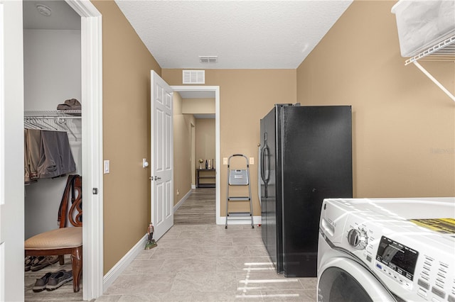 laundry room with a textured ceiling, light tile patterned floors, and washer / dryer