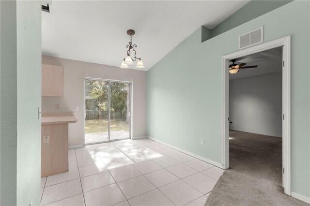 unfurnished dining area featuring vaulted ceiling, light tile patterned flooring, and ceiling fan with notable chandelier