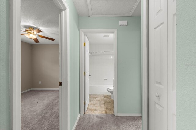 hall featuring light colored carpet and a textured ceiling