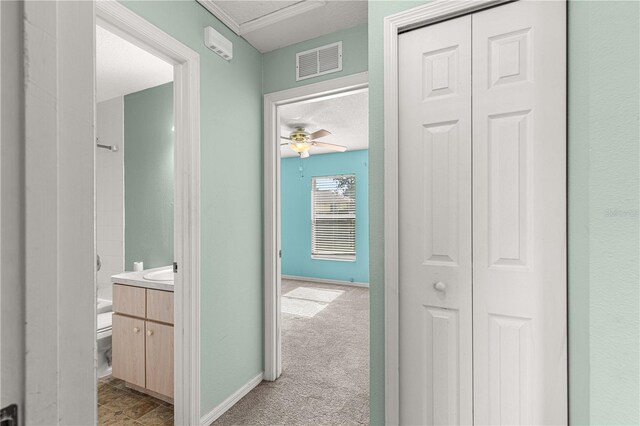 hallway with a textured ceiling, light carpet, and sink