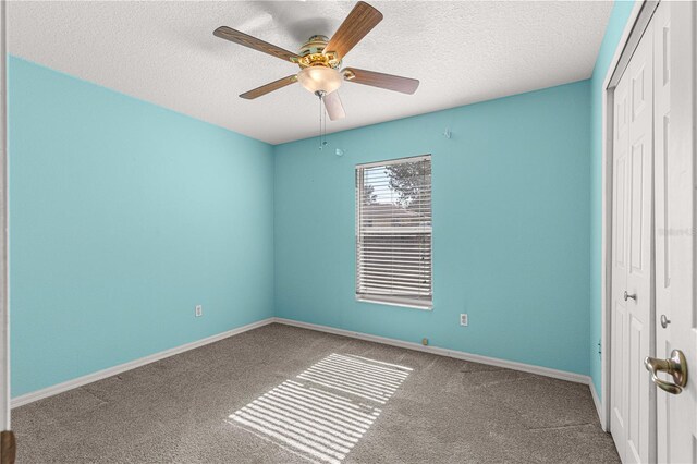 carpeted spare room with a textured ceiling and ceiling fan