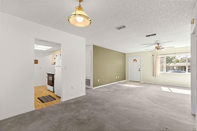 unfurnished living room with a textured ceiling, carpet flooring, and ceiling fan