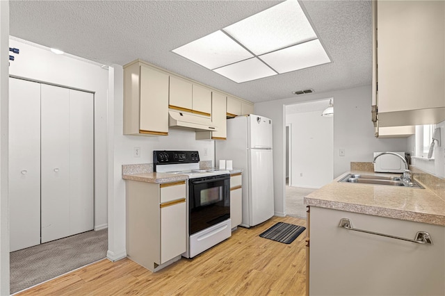 kitchen with sink, a textured ceiling, white appliances, cream cabinetry, and light wood-type flooring