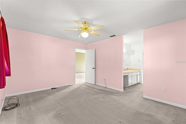 carpeted spare room featuring a textured ceiling, ceiling fan, and sink