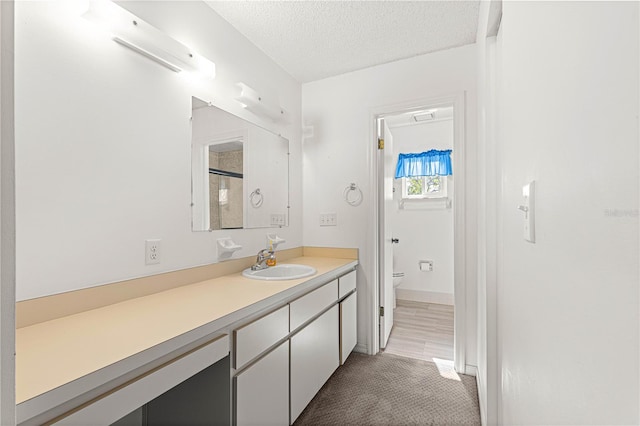 bathroom featuring a shower with door, a textured ceiling, hardwood / wood-style floors, vanity, and toilet