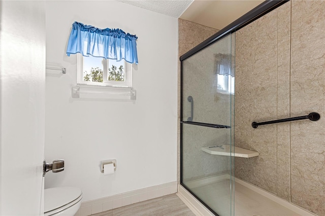 bathroom with an enclosed shower, wood-type flooring, a textured ceiling, and toilet