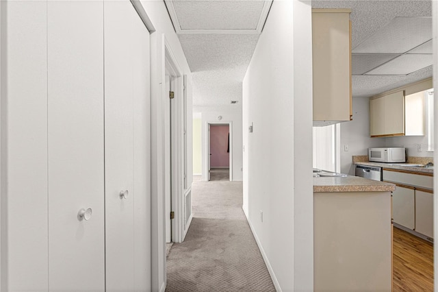 hall with a textured ceiling and light colored carpet