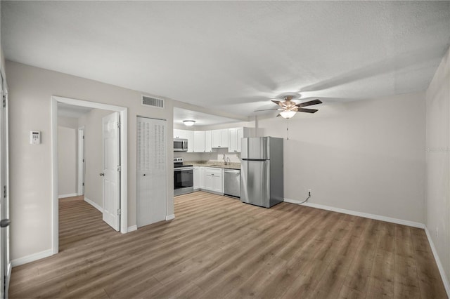 kitchen featuring stainless steel appliances, white cabinetry, light hardwood / wood-style floors, and sink