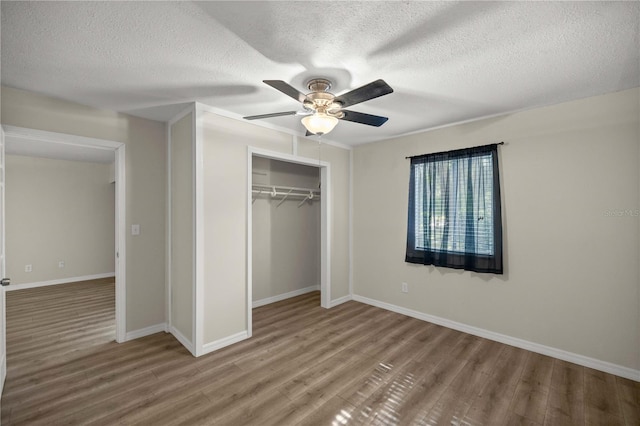 unfurnished bedroom with a closet, hardwood / wood-style floors, ceiling fan, and a textured ceiling