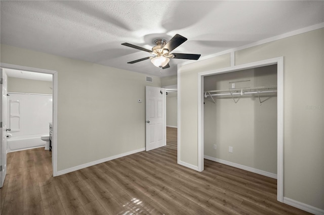 unfurnished bedroom featuring a closet, ensuite bath, ceiling fan, and dark hardwood / wood-style flooring