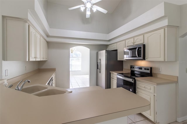 kitchen with stainless steel appliances, ceiling fan, sink, high vaulted ceiling, and light tile patterned flooring