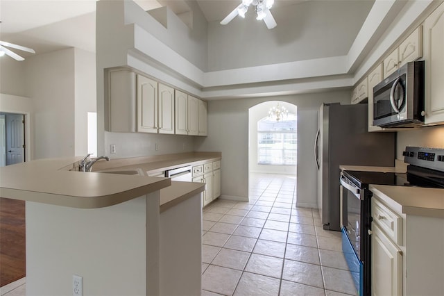 kitchen featuring ceiling fan with notable chandelier, sink, light tile patterned floors, kitchen peninsula, and stainless steel appliances