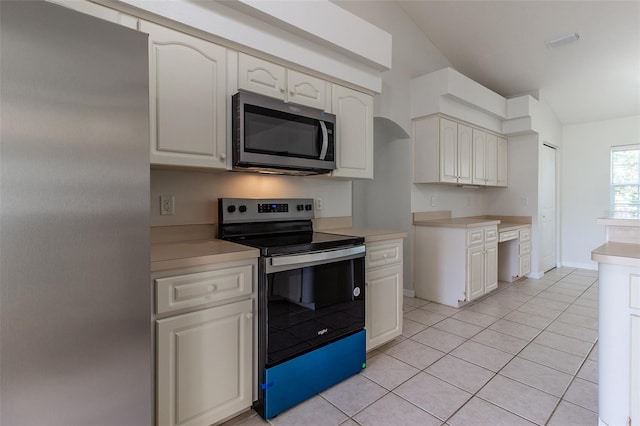 kitchen featuring light tile patterned flooring, stainless steel appliances, and vaulted ceiling