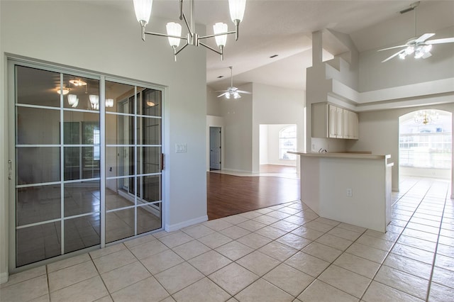 kitchen featuring ceiling fan with notable chandelier, high vaulted ceiling, and light hardwood / wood-style flooring